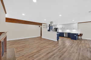 Kitchen featuring open floor plan, light wood finished floors, light countertops, a peninsula, and recessed lighting