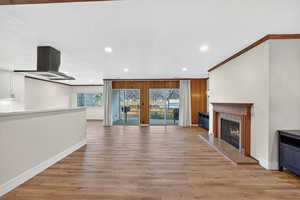 Unfurnished living room with ornamental molding, light wood-style flooring, recessed lighting, and a premium fireplace