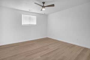 Empty room with ceiling fan, wood finished floors, and concrete block wall