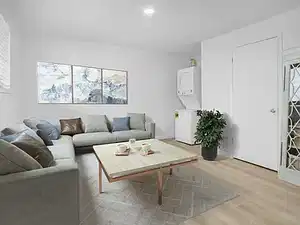 Living room featuring wood finished floors, stacked washing machine and dryer, and recessed lighting