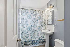 Full bathroom with toilet and shower / bath combination with curtain