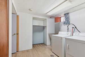 Laundry area with light wood-type flooring and washer and clothes dryer