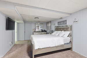 Bedroom with light colored carpet and wooden walls