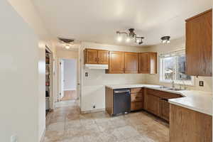 Kitchen with wood finish cabinetry, light countertops, and stainless steel dishwasher