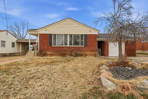 View of front of home with brick siding, driveway, a garage, and a front yard
