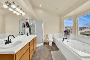 Bathroom with a tub with jets, a stall shower, double vanity, recessed lighting, and lofted ceiling