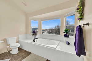 Full bath featuring a jetted tub and lofted ceiling