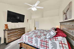 Carpeted bedroom featuring vaulted ceiling and ceiling fan
