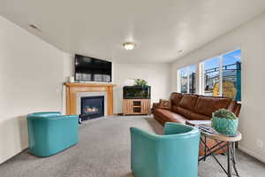 Living area with a fireplace, carpet, and a textured ceiling