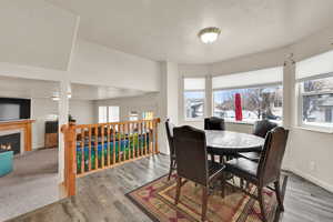 Dining room with wood finished floors, a tile fireplace, healthy amount of natural light, and a textured ceiling