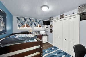 Bedroom featuring a textured ceiling, a closet, and dark wood-type flooring
