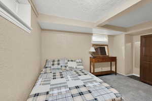 Bedroom featuring dark carpet, a textured ceiling, and a textured wall