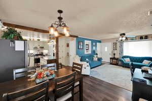Dining space featuring dark wood-type flooring, a textured ceiling, hanging lights, ceiling fan, and a baseboard heating unit
