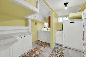 Laundry area featuring concrete floors, washer and clothes dryer, and cabinet space