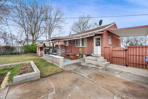 View of front of home featuring a patio area, brick siding, and a gate