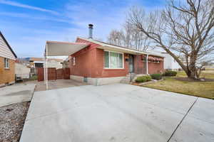 View of front facade featuring brick siding, concrete driveway, and an attached carport