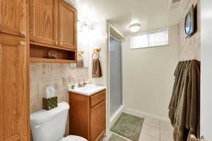 Bathroom with a textured ceiling, a shower stall, vanity, and light tile patterned floors
