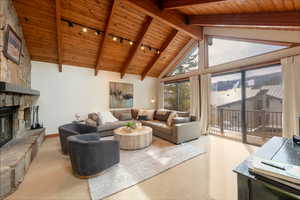 Living room with a fireplace, a high wood beamed ceiling, and carpet
