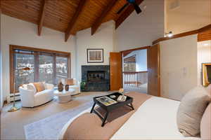 Carpeted living area featuring a high wood beamed ceiling, a high end fireplace, baseboard heating, and a ceiling fan