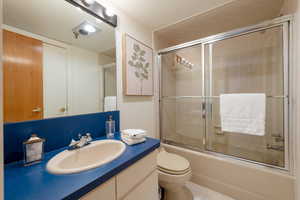 Bathroom featuring shower / bath combination with glass door, vanity, and tile patterned flooring