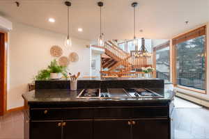 Kitchen with baseboard heating, light tile patterned floors, a kitchen island, dark cabinets, and electric cooktop