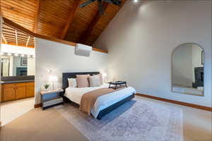 Bedroom with a tile fireplace, light colored carpet, and a high wood beamed ceiling