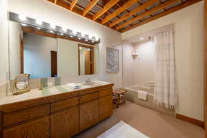 Bathroom with shower / bathtub combination with curtain, vanity, and light colored carpet
