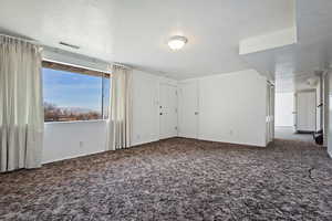 Empty room with a textured ceiling and dark carpet