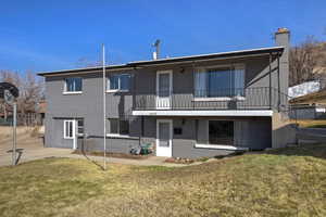 Rear view of property with a balcony, a chimney, and brick siding