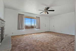 Unfurnished living room with a ceiling fan, carpet floors, and a fireplace