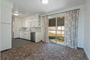 Kitchen featuring white cabinets, dark colored carpet, light countertops, and glass insert cabinets