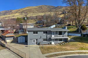 View of front facade with a chimney, a mountain view, a shed, and brick siding