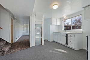 Kitchen featuring white cabinetry, light countertops, a textured ceiling, and dark colored carpet