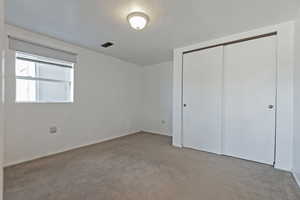 Unfurnished bedroom with light carpet and a closet