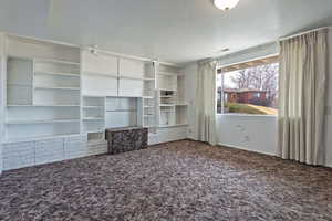 Unfurnished living room with a textured ceiling and dark colored carpet
