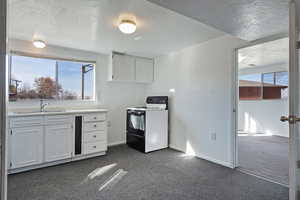 Kitchen with white cabinetry, a textured ceiling, dark carpet, light countertops, and white range with electric stovetop