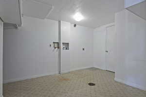 Laundry area with a textured ceiling, hookup for a washing machine, and light floors
