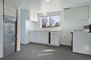 Kitchen featuring white cabinets, a textured ceiling, light countertops, dark carpet, and washer / dryer