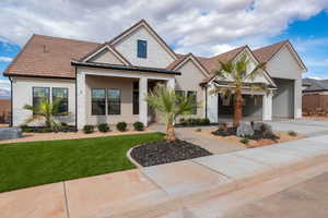 View of front facade with a front yard, brick siding, a porch, concrete driveway, and a garage