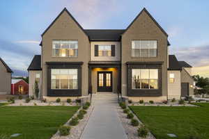 View of front of property with a front lawn, brick siding, french doors, and a shingled roof