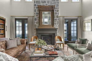 Living area with french doors, a high ceiling, plenty of natural light, a glass covered fireplace, and wood finished floors