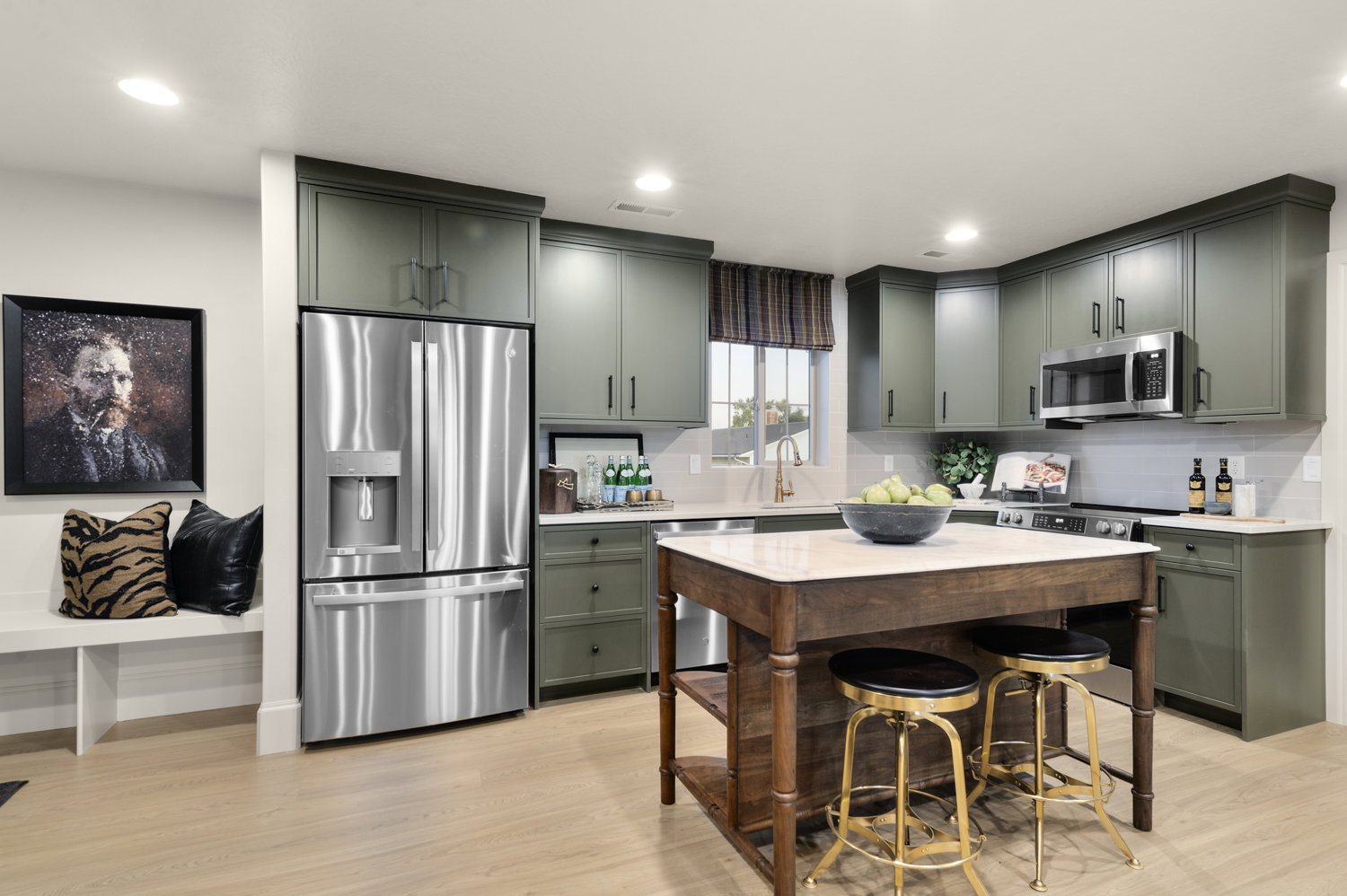 Kitchen with green cabinets, stainless steel appliances, light wood-style flooring, tasteful backsplash, and light stone countertops