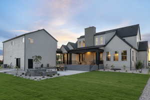 Rear view of house with a patio area, a lawn, and a chimney