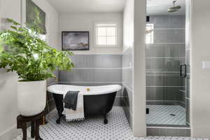 Bathroom featuring a shower stall, tile walls, and a freestanding bath