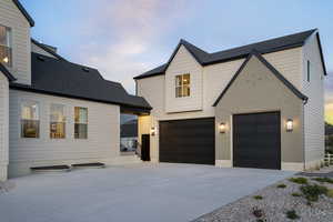 View of front of home with an attached garage, driveway, and roof with shingles