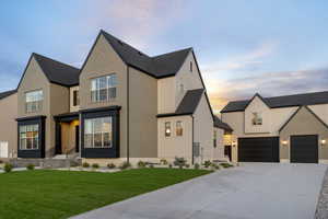 View of front facade featuring a lawn, concrete driveway, brick siding, and a shingled roof