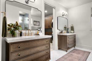 Full bath with two vanities, a shower stall, and light flooring
