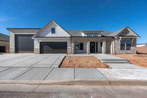 View of front of property with stone siding, a porch, a standing seam roof, concrete driveway, and a garage