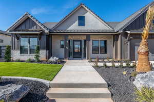 View of front of property featuring brick siding, covered porch, board and batten siding, and a front yard