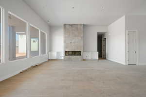 Unfurnished living room featuring a tiled fireplace and light wood-type flooring
